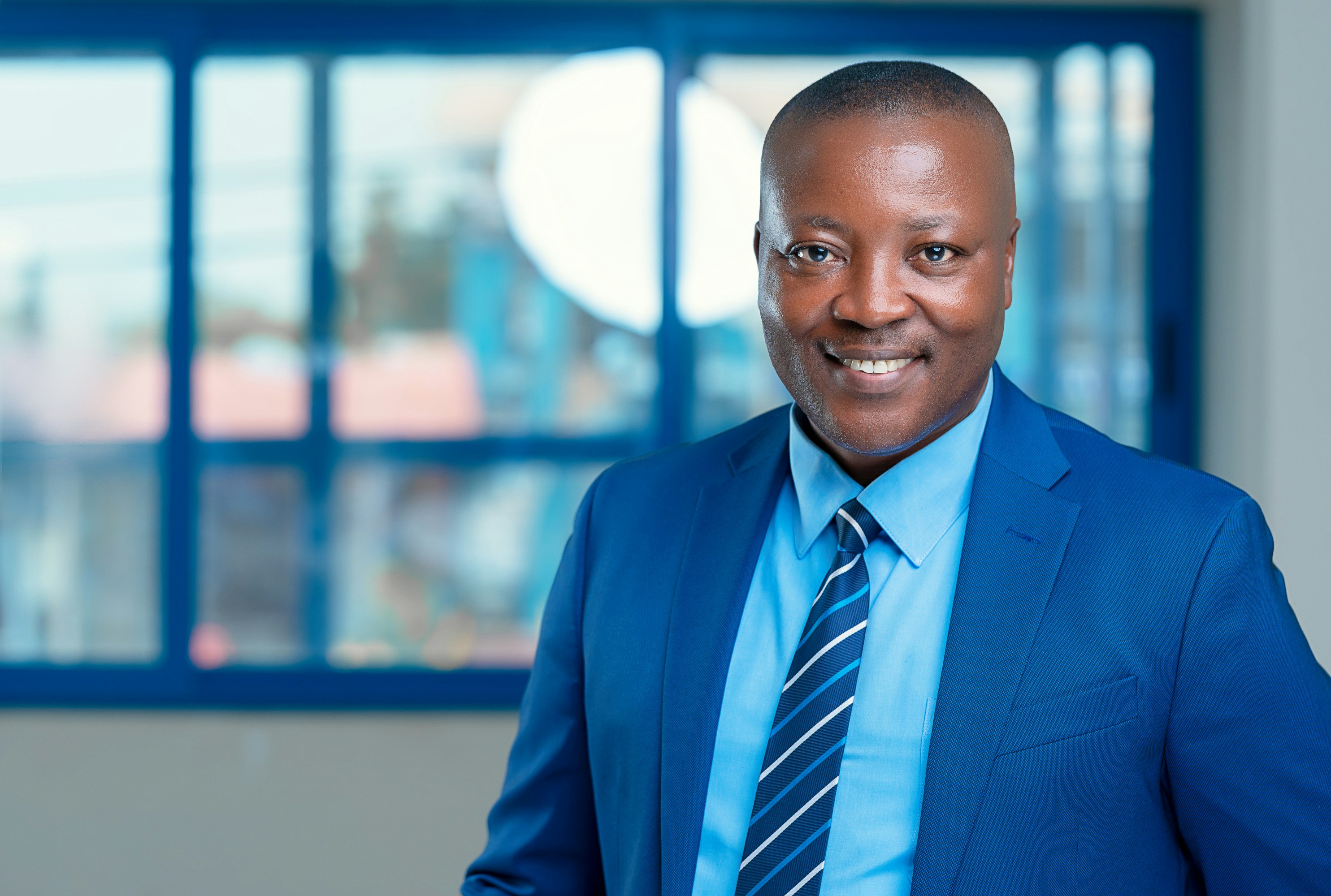 Professionnel africain souriant en costume bleu dans un environnement de bureau